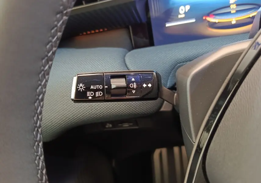 Gros plan sur la commande des feux et clignotants à gauche du volant dans l’habitacle du Citroën C5 Hybride vert.