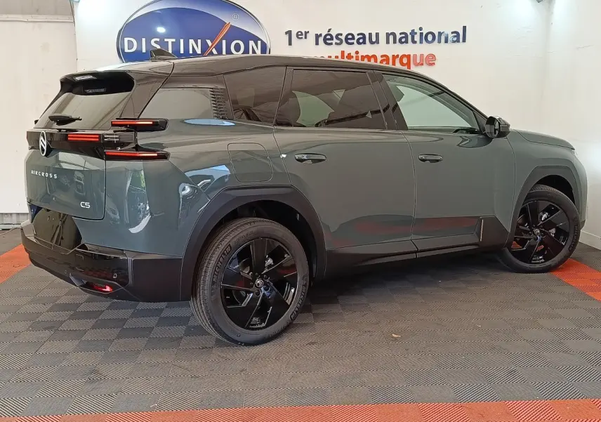 Vue 3/4 arrière droite d'une Citroën C5 Aircross hybride 2026 vert avec jantes noires et toit noir brillant.