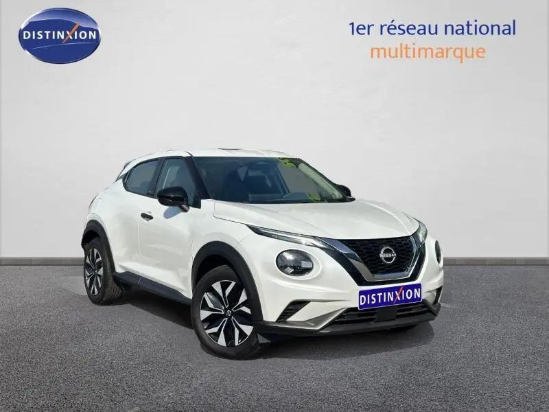 Nissan Juke blanc nacré vue 3/4 avant droit, avec calandre noire et jantes bicolores distinctives.