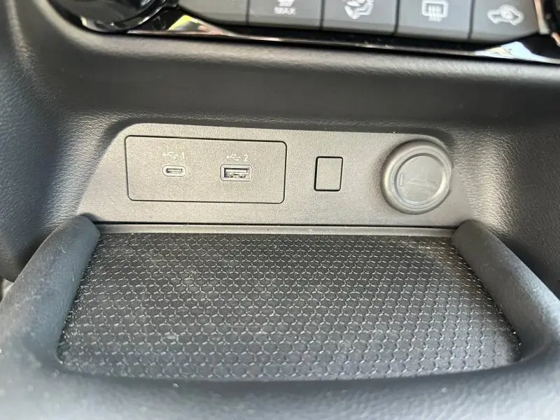 Gros plan sur la console centrale noire du Nissan Juke 2025 montrant les ports USB et la prise 12V.