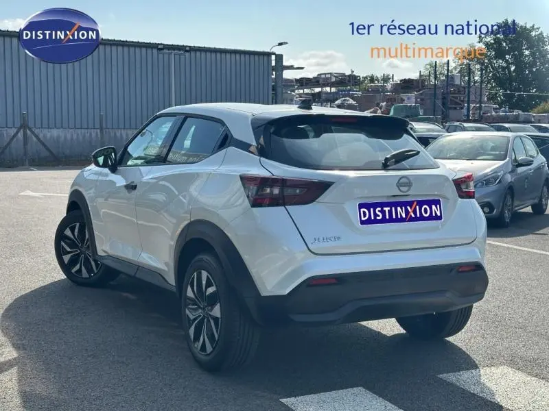 Vue 3/4 arrière droite d'un Nissan Juke blanc nacré spécial 2025 avec jantes noires et toit noir contrasté.