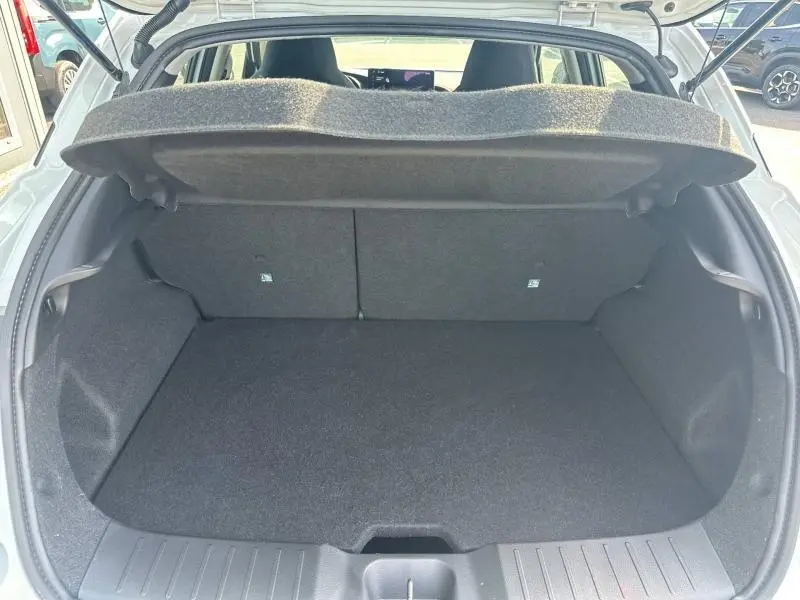 Coffre ouvert vu de l'arrière du Nissan Juke blanc nacré 2025, montrant un espace de chargement propre et spacieux.