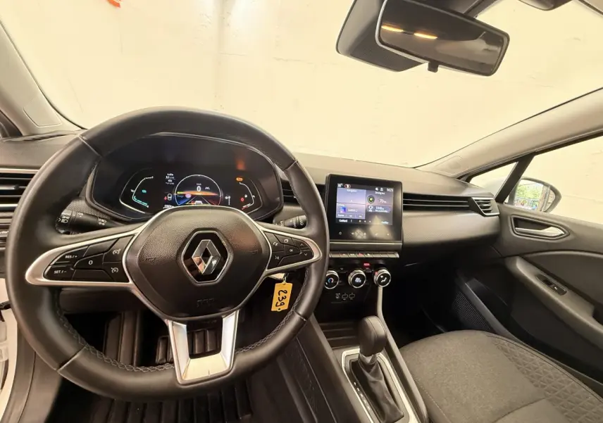 Vue intérieure avant de la Renault Clio Business E-Tech hybride blanche 2022, volant cuir multifonctions et écran tactile central.