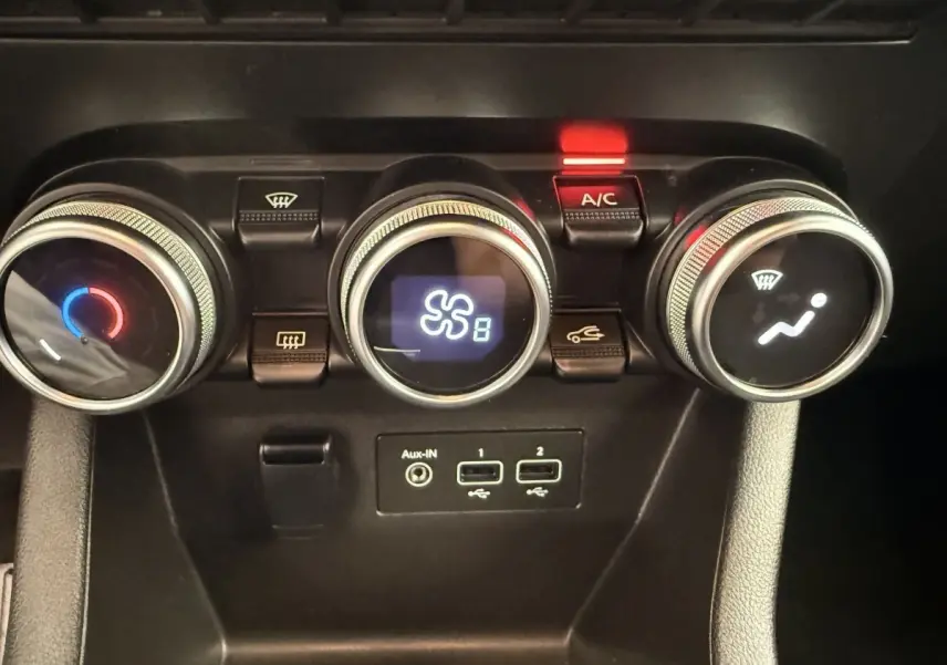 Vue rapprochée des commandes de climatisation avec trois molettes et ports USB dans une Renault Clio blanche hybride 2022.