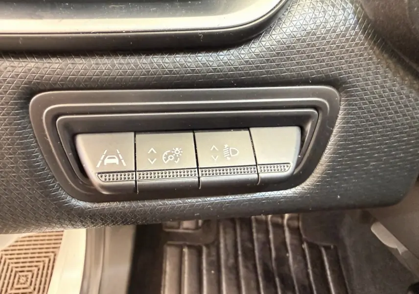 Gros plan sur les boutons de réglage d'assistance à la conduite dans une Renault Clio Business E-Tech hybride blanche.
