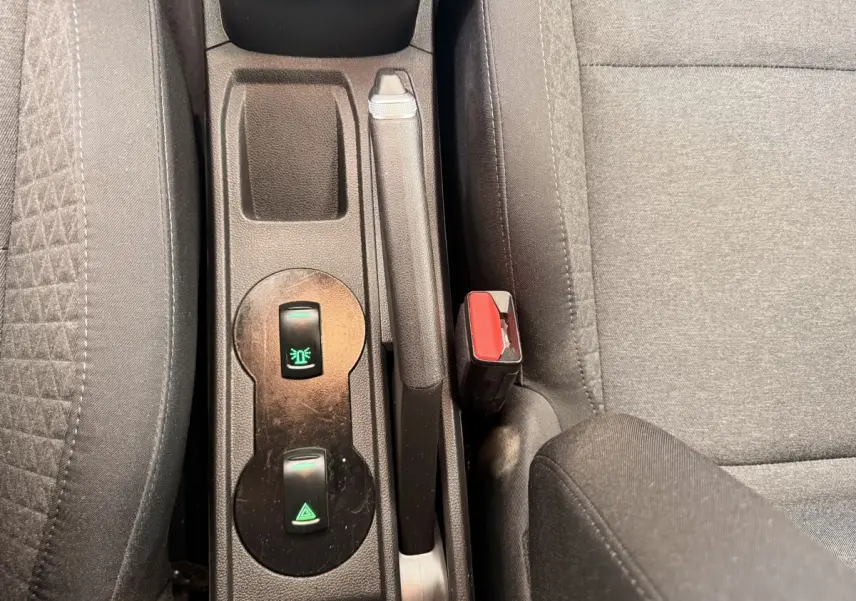 Vue rapprochée de la console centrale intérieure de la Renault Clio blanche, montrant frein à main et boutons de commande.