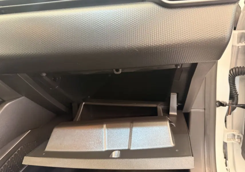Gros plan sur la boîte à gants ouverte côté passager d’une Renault Clio Business E-Tech blanche, intérieur noir.