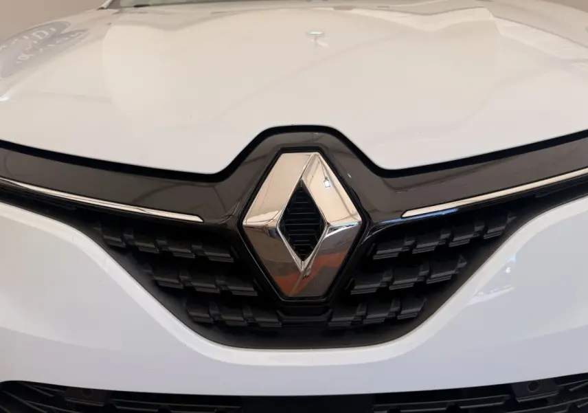 Gros plan sur la calandre avant blanche d'une Renault Clio Business E-Tech hybride 2022 avec logo chromé central.