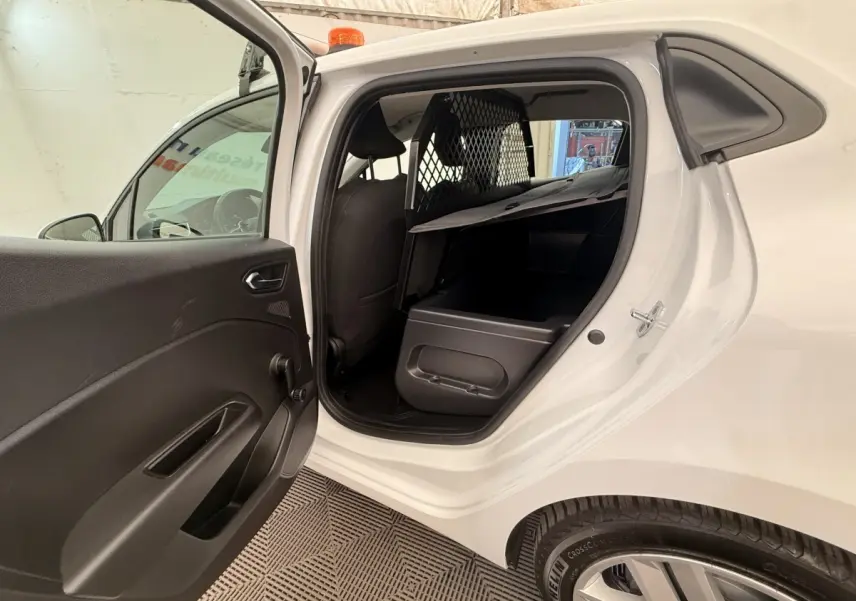 Vue côté gauche arrière d'une Renault Clio blanche 2022 avec porte ouverte, montrant l'intérieur et la grille de séparation.