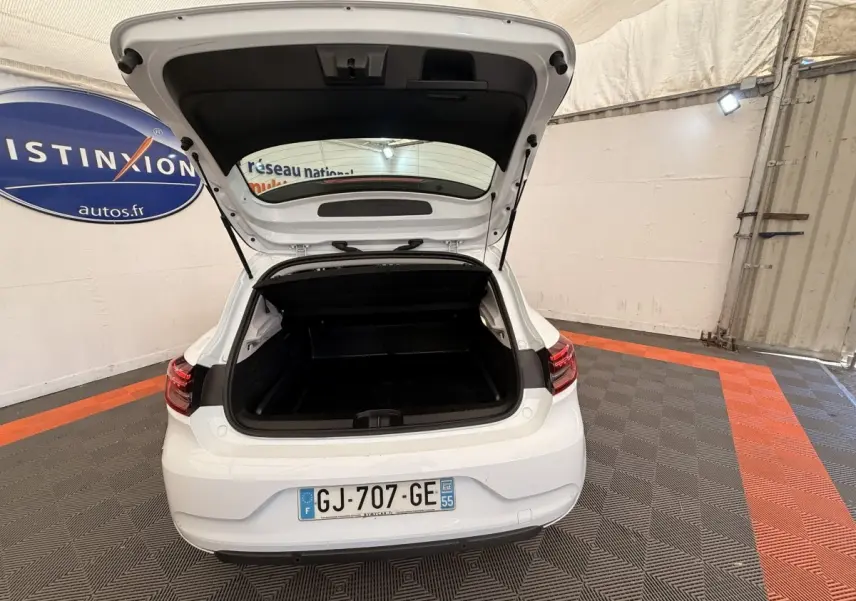 Vue arrière d'une Renault Clio Business E-Tech hybride blanche 2022 avec coffre ouvert dans un garage.