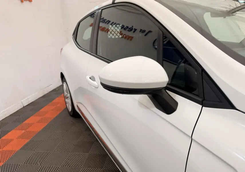 Vue rapprochée côté gauche d'une Renault Clio Business E-Tech hybride blanche, mettant en valeur le rétroviseur et la portière.