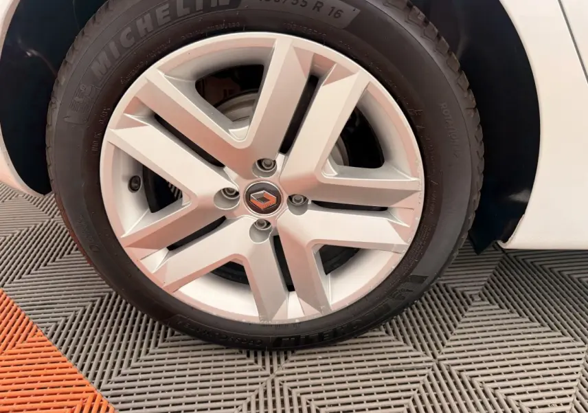 Gros plan sur la roue avant droite d'une Renault Clio blanche, mettant en valeur la jante alliage et le pneu Michelin.