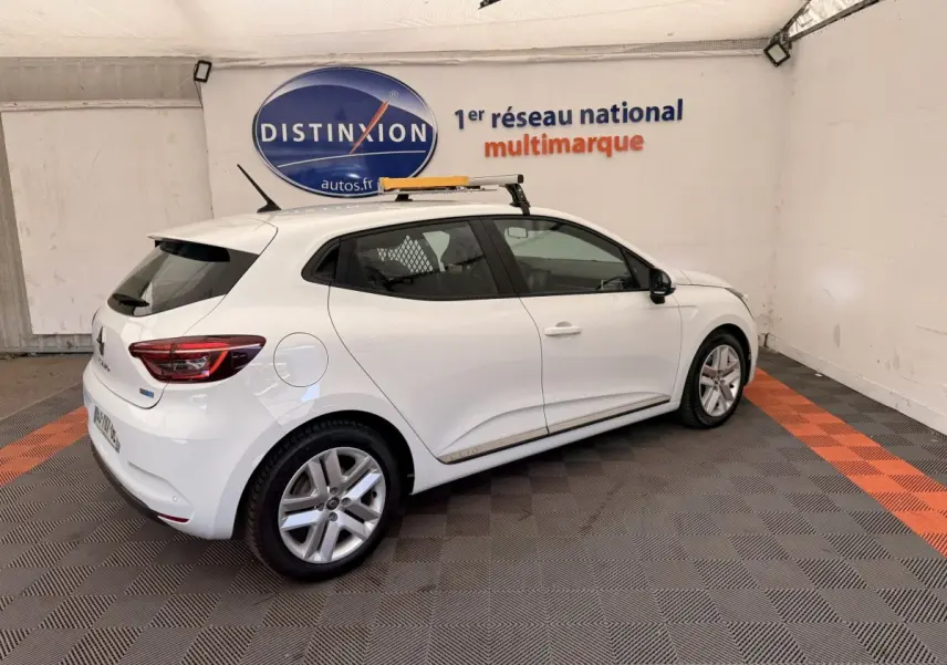 Renault Clio Business E-Tech hybride blanc vue 3/4 arrière droit en intérieur avec toit équipé d'une galerie.