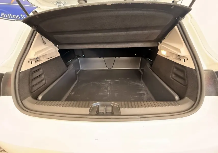 Coffre ouvert vu de l'arrière d'une Renault Clio Business E-Tech hybride blanche, avec tapis de protection noir.