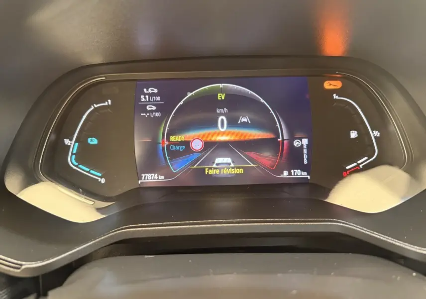 Gros plan sur le combiné d'instruments numérique de la Renault Clio Business E-Tech hybride blanc, affichant 0 km/h et message "Faire révision".