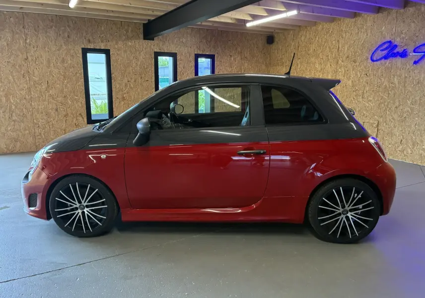 Vue latérale gauche de l'Abarth 500 Competizione rouge avec toit noir et jantes alliage noires à rayons fins.