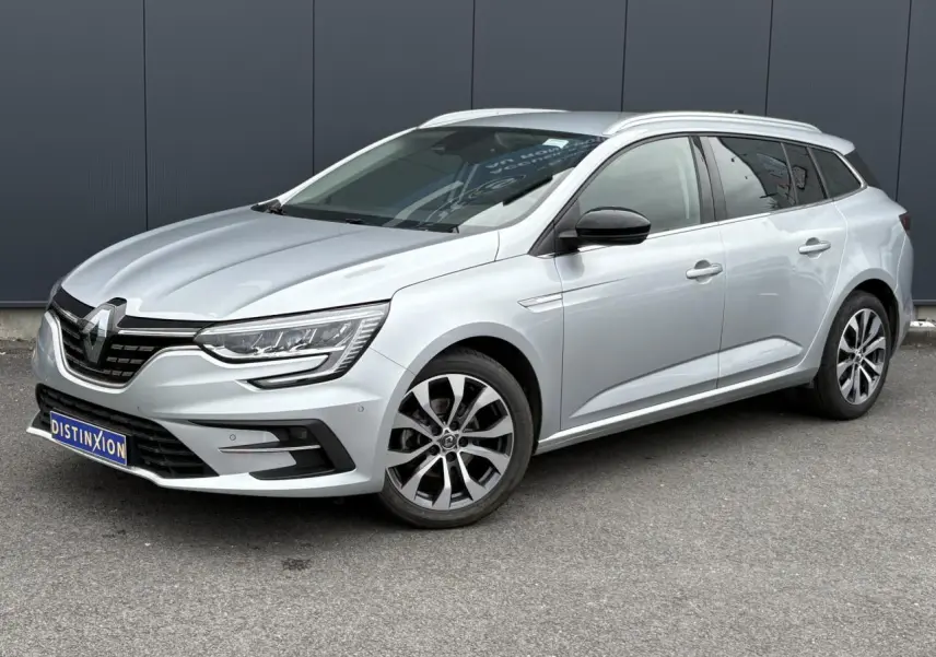 Renault Mégane Break gris clair en 3/4 avant droit, avec jantes alliage et calandre noire distinctive.