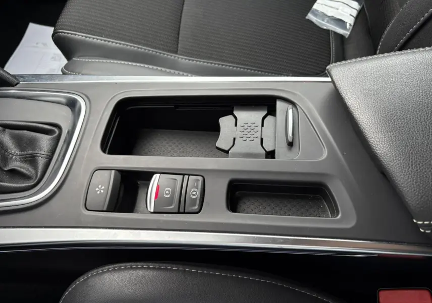 Vue rapprochée de la console centrale noire du Renault Mégane Break 2024 avec commandes de frein à main électrique et rangement.