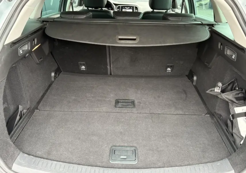 Coffre spacieux gris foncé de la Renault Mégane Break 2024 avec cache-bagages et banquette arrière visible.