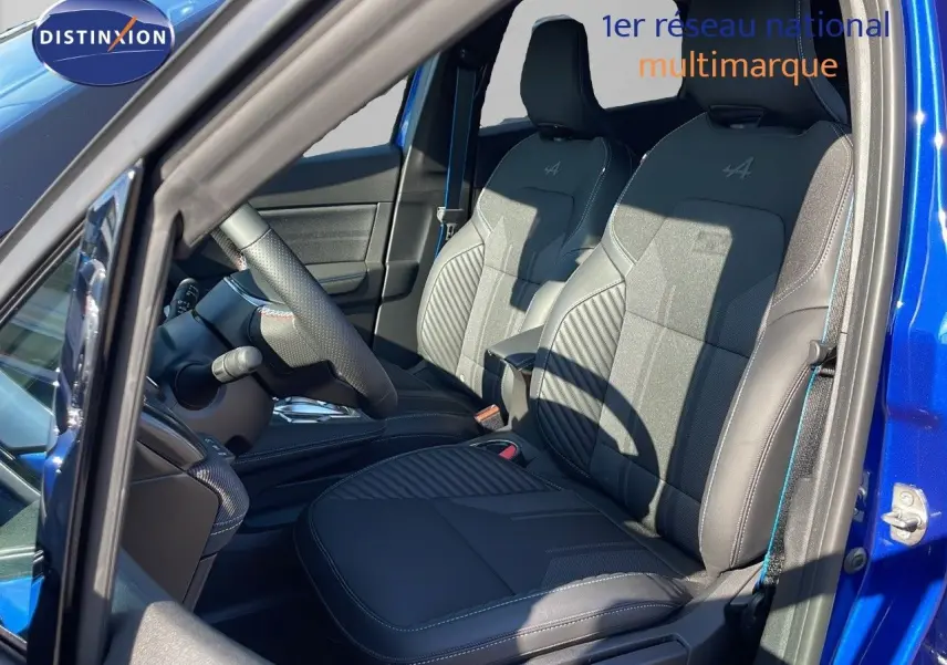 Vue intérieure côté conducteur du Renault Captur E-Tech hybride 2025 avec sièges noirs Alpine et portière bleu iron metal ouverte.