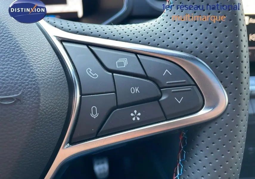 Gros plan sur les commandes multifonctions du volant en cuir perforé du Renault Captur E-Tech hybride 2025.