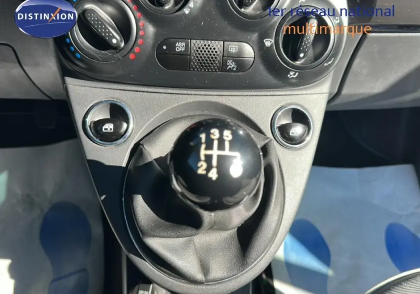 Le levier de vitesses manuel noir de la FIAT 500 Lounge 2016, avec commandes de climatisation en arrière-plan.