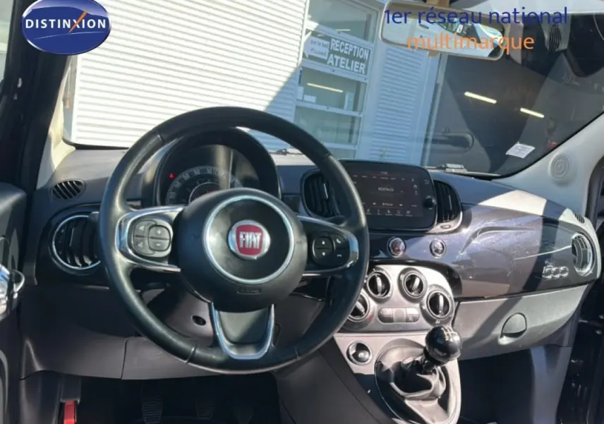 Vue intérieure avant du tableau de bord et volant noir de la Fiat 500 Lounge 2016 avec boîte manuelle et écran tactile central.