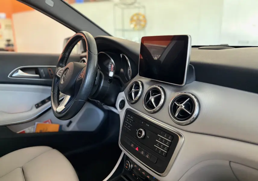 Vue intérieure côté conducteur du Mercedes GLA 200D Business gris, avec tableau de bord clair et écran tactile central.