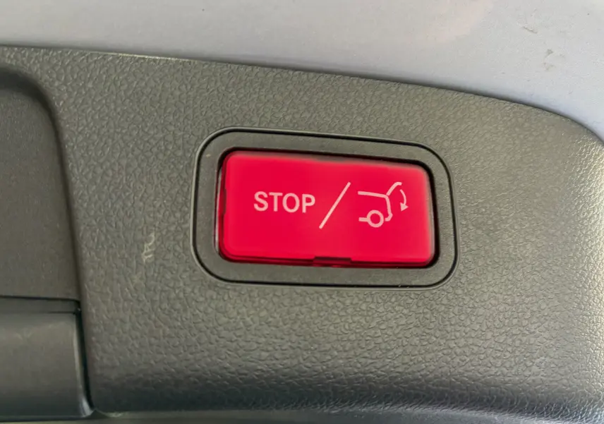 Bouton rouge "STOP" pour ouverture/fermeture électrique du coffre, vue rapprochée à l'intérieur d'une Mercedes GLA 200D Business gris.