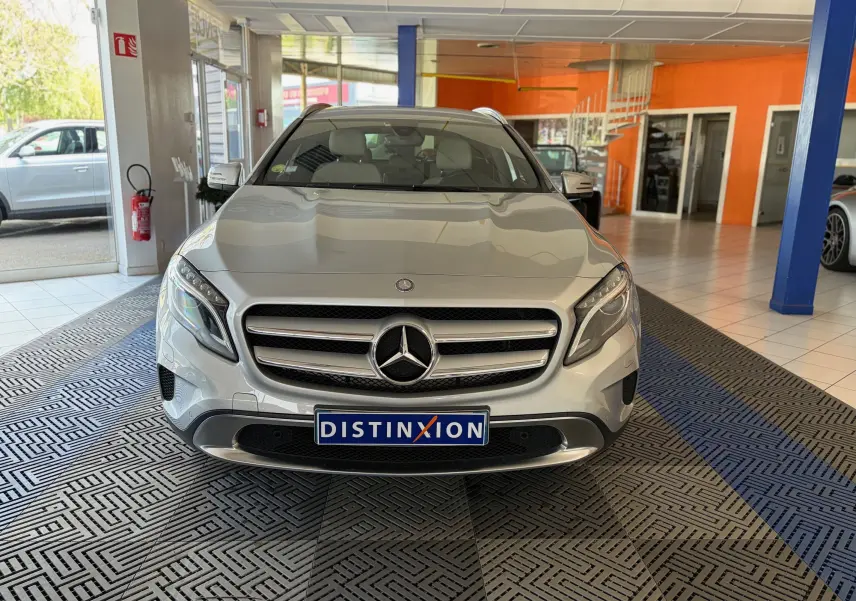 Vue frontale d'un Mercedes GLA 200D Business gris, avec calandre chromée et phares LED, en intérieur showroom.