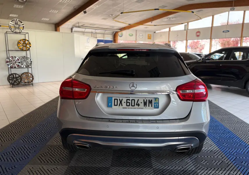 Vue arrière d'un Mercedes GLA 200D Business gris dans un showroom, avec feux rouges et double sortie d'échappement.