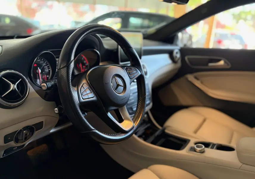Intérieur beige clair de Mercedes GLA 200D Business 2015, vue côté conducteur avec volant cuir noir et tableau de bord moderne.