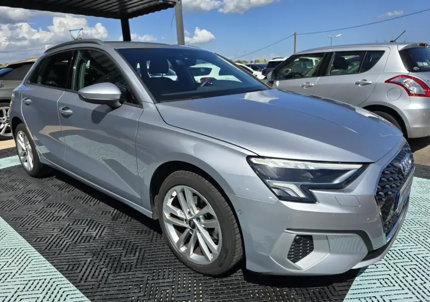 Audi A3 Sportback gris argent fleuret vue 3/4 avant droit, avec phares LED et jantes alliage 17 pouces.