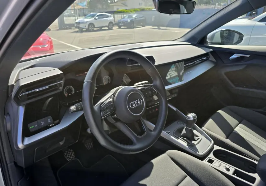 Vue intérieure côté conducteur de l'Audi A3 Sportback 2022 avec volant cuir, boîte manuelle et tableau de bord moderne.