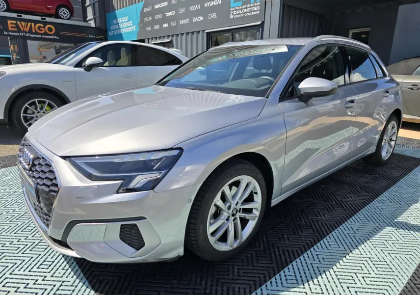 Audi A3 Sportback gris argent fleuret vue 3/4 avant droit, jantes alliage 17 pouces et phares LED visibles.