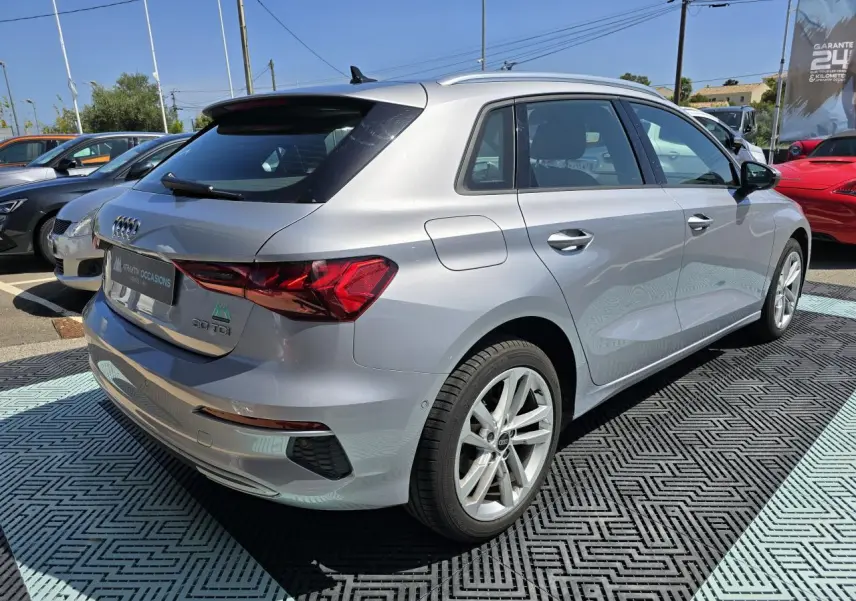 Audi A3 Sportback gris argent fleuret vue 3/4 arrière droit avec jantes alliage 17 pouces sur parking extérieur.