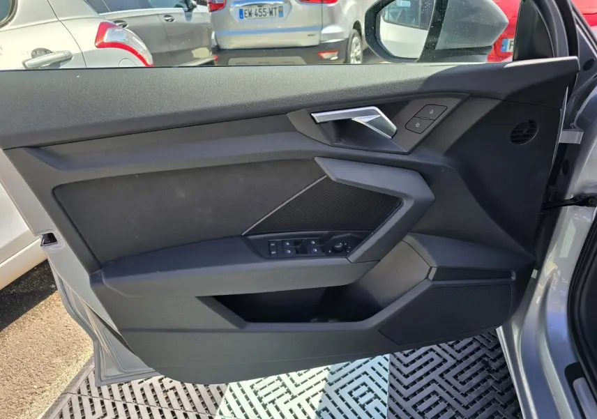 Vue intérieure côté gauche de la porte avant gris argent d'une Audi A3 Sportback 2022 avec commandes de vitres et poignée métallique.