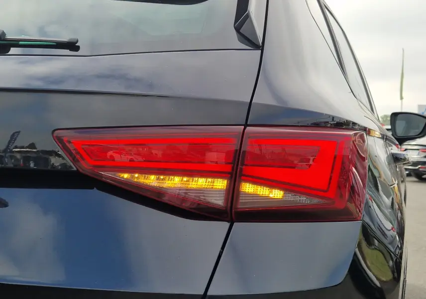 Gros plan sur le feu arrière droit allumé d’un SEAT Ateca noir 2023, soulignant la carrosserie brillante et les lignes anguleuses.