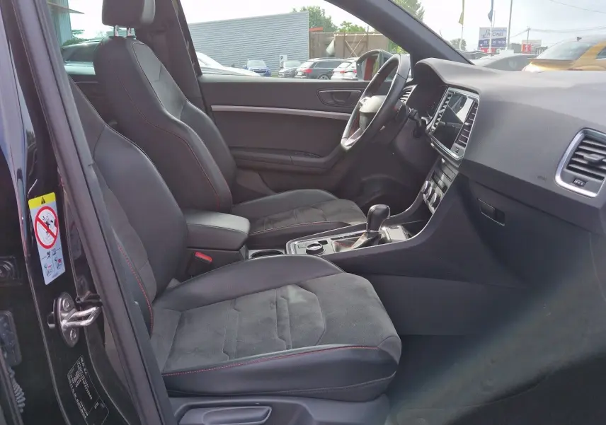 Vue intérieure côté conducteur du SEAT Ateca noir 2023, avec toit panoramique, sièges sport et tableau de bord numérique.