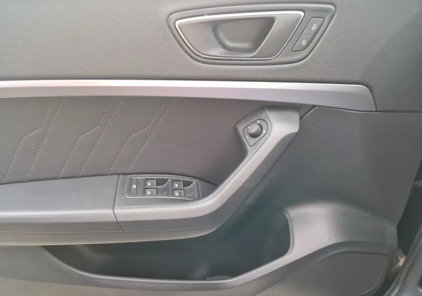 Vue rapprochée de la porte côté conducteur du SEAT Ateca noire 2023, avec commandes électriques et poignée intégrée.