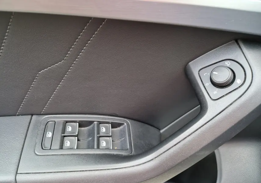 Gros plan sur la commande des vitres et réglage des rétroviseurs côté gauche intérieur d’un SEAT Ateca noir 2023.