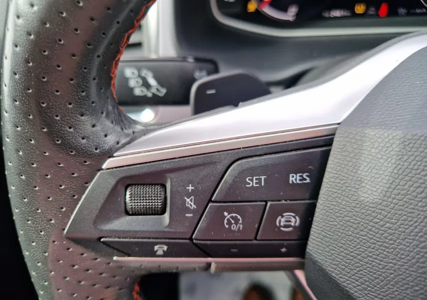 Gros plan sur les commandes au volant en cuir perforé noir avec surpiqûres rouges du SEAT Ateca 2023.
