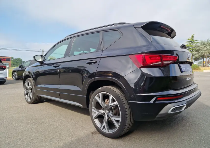 Vue 3/4 arrière droite d’un SEAT Ateca noir 2023 avec jantes alu 19 pouces et hayon électrique en extérieur.