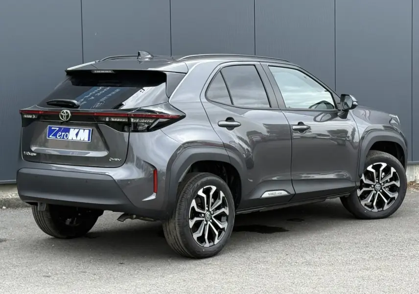 Vue 3/4 arrière droite d'une Toyota Yaris Cross 1.5 Hybrid gris Atlas avec jantes alliage et feux arrière LED.