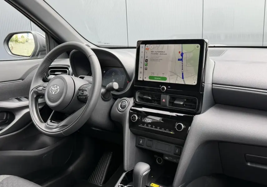 Vue intérieure avant droite du Toyota Yaris Cross gris Atlas 2026, avec écran tactile central et volant cuir.