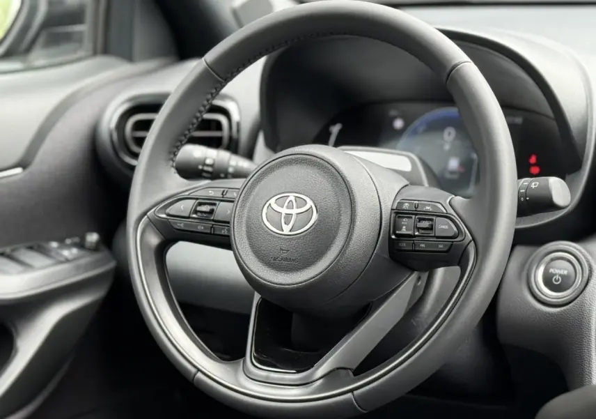 Vue rapprochée du volant cuir noir de la Toyota Yaris Cross 2026 avec commandes intégrées et bouton start.