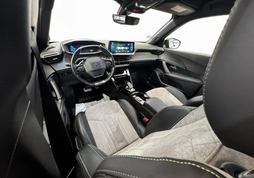 Intérieur de la Peugeot E-2008 GT Pack électrique 2021, vue avant droite, sièges tissu gris et cuir noir, tableau de bord digital.