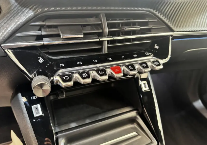 Gros plan sur la console centrale noire du Peugeot E-2008 électrique GT Pack 2021 avec boutons de commande et aérateurs.