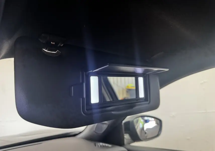 Détail du miroir de courtoisie éclairé sur pare-soleil intérieur côté gauche d’un Peugeot E-2008 noir électrique.