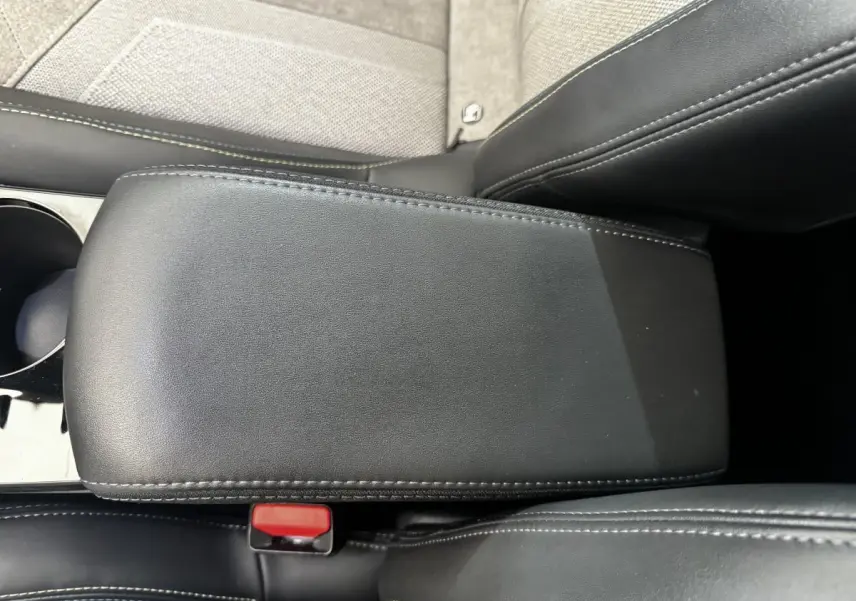Gros plan sur l'accoudoir central en cuir noir avec surpiqûres blanches dans l'habitacle du Peugeot E-2008 électrique.